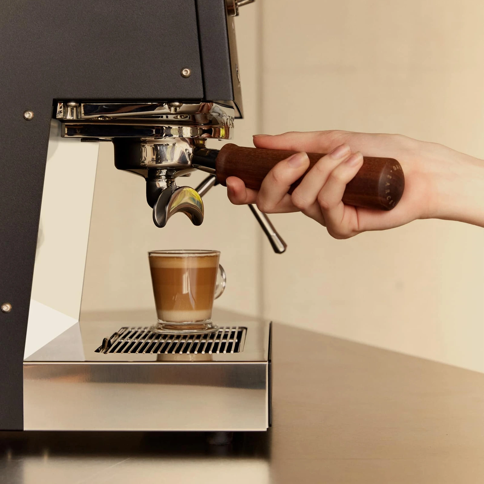 Black „Ascaso“ Steel DUO PLUS pouring espresso into a glass cup on the stainless steel drip tray grille
